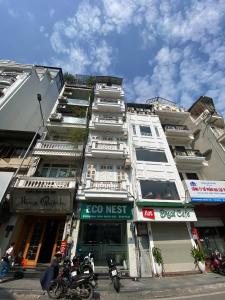 a tall white building with motorcycles parked in front of it at Eco Nest Hotel 6 Đình Ngang in Hanoi