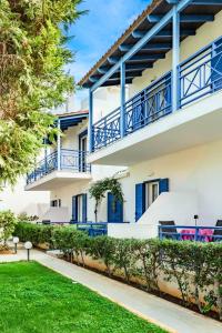 an apartment building with blue balconies and a yard at Cretan Dawn Apart, Value Option in Ammoudara in Ayía Marína +5 photos
