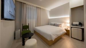 a hotel room with a bed and a television at Maison The Denbasta Hotel in Busan