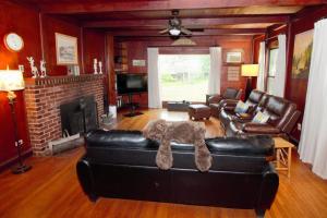 a living room with a black leather couch and a fireplace at The Cabin at Deer Hollow in Three Rivers