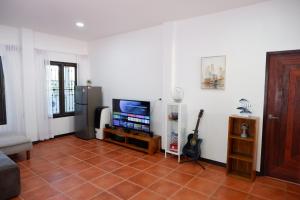 a living room with a tv and a tiled floor at Pran Botanica Private Pool Villa in Ban Rom Pho