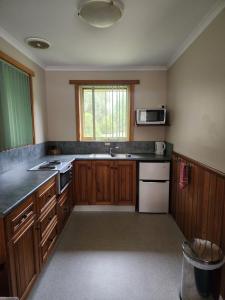 a kitchen with wooden cabinets and a sink and a microwave at Kentish Hills Retreat in Sheffield