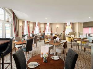a restaurant with wooden tables and chairs and windows at Mercure Doncaster Centre Danum Hotel in Doncaster