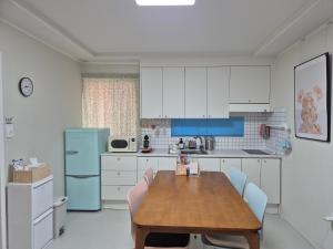 a kitchen with a wooden table and a blue refrigerator at 어게인수영 in Suyŏng