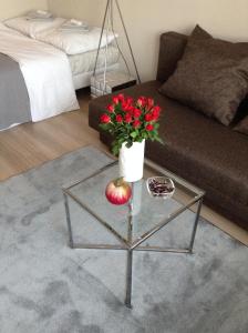 uma sala de estar com uma mesa de vidro com um vaso com flores vermelhas em Apartament Kiza em Kielce