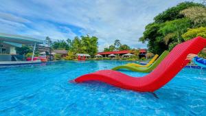 a red chair in the water at a swimming pool at Casa Marcos Resort and Villas in Pastrana