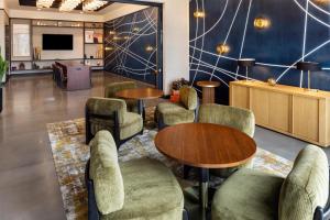 a waiting room with tables and chairs and a tv at Tempo By Hilton Manassas in Manassas