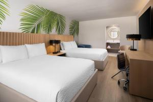 a hotel room with two beds and a desk at The Harrison Hotel Downtown Hollywood FL, an Ascend Collection Hotel in Hollywood
