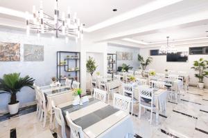 a dining room with white tables and white chairs at Merhaba Hotel, Fergana in Fergana