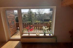 a window with vases of flowers on a balcony at Ferienwohnung Lechauszeit in Landsberg am Lech