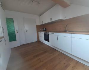 a large kitchen with white cabinets and a wooden floor at Ferienwohnung Lechauszeit in Landsberg am Lech +2 photos