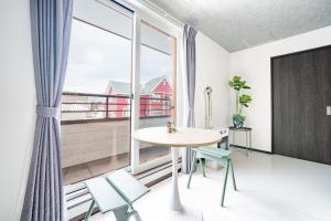 a room with a table and chairs and a large window at Hills Niseko 206 in Wada