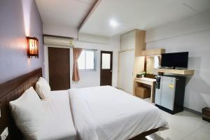 a bedroom with a white bed and a television at 100House Hotel Korat in Ban Hua La Loeng