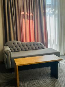 a couch sitting in front of a window with a coffee table at Golden Palace Hotel in Almaty