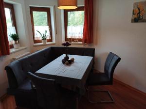 a dining room with a table and chairs and windows at Ferienwohnung am Ulrichsgrünbach in Waldmünchen