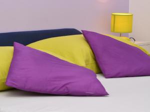 three purple and yellow pillows on a bed at Apartment T&M in Trogir
