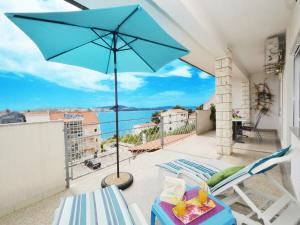 a patio with a blue umbrella and chairs on a balcony at Apartment T&M in Trogir