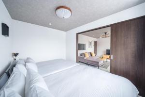 a bedroom with a large white bed with a mirror at Hills Niseko 206 in Wada