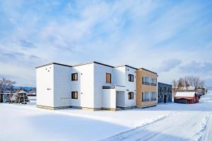 a white building in the snow on a snowy street at Hills Niseko 206 in Wada