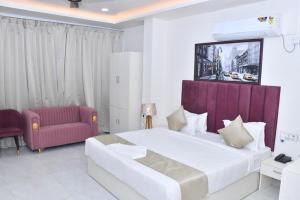 a bedroom with a large bed and a red chair at Bisaka Hotels in Patna