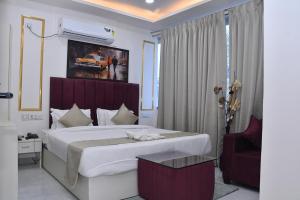 a bedroom with a large white bed and a chair at Bisaka Hotels in Patna