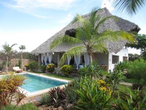 a house with a thatched roof and a swimming pool at Villa Isla del Amore in Watamu