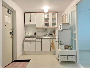 a kitchen with white cabinets and a white refrigerator at Gold Stream House in Seoul