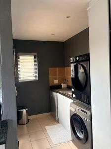 a kitchen with a washing machine and a microwave at Tranquil Arcade in Boschrand