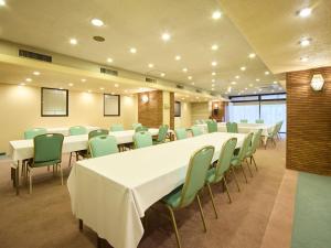 a conference room with white tables and green chairs at Hotel Pearl City Morioka in Morioka