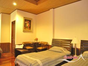 a bedroom with a bed and a table and chairs at บ้านไร่คุณนาย in Ban Sap Bon