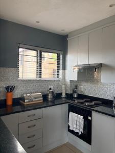 a kitchen with white cabinets and a stove top oven at Tranquil Arcade in Boschrand