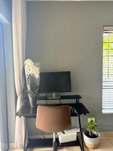 a desk with a vase of flowers and a chair at Tranquil Arcade in Boschrand +4 photos