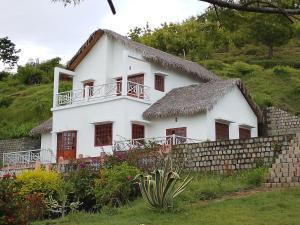 a white house with a thatch roof at Greengardenlodge in Nosy Be