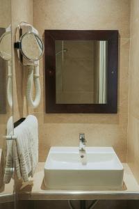 a bathroom with a white sink and a mirror at Hotel Cosmos in Paris +38 photos