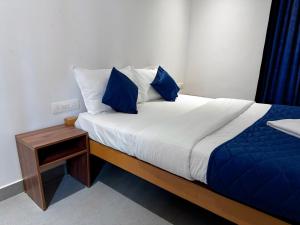 a bed with blue and white sheets and a night stand at Havana Beach Villa in Alleppey