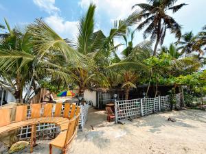 a wooden bench on a beach with palm trees at Havana Beach Villa in Alleppey