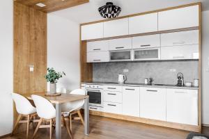 a kitchen with white cabinets and a wooden table and chairs at Jen tak Lipno in Lipno nad Vltavou