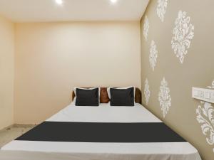 a bedroom with a bed with black and white pillows at Hotel O BSS INNS in Warangal