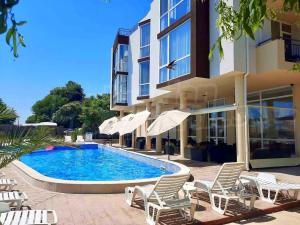 a swimming pool with chairs and umbrellas next to a building at Royal Marina Beach in Chernomorets
