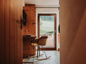 a room with a chair and a table and a window at Hotel Schönberg in Rio Bianco