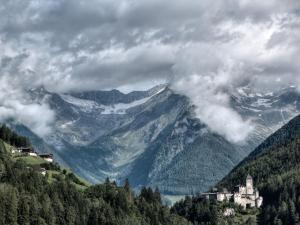 a castle on top of a mountain with clouds at Hotel Schönberg in Rio Bianco