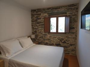 a bed in a room with a stone wall at Quinta da Valdigueira in Armamar
