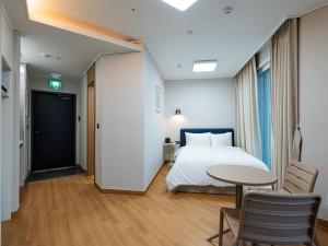 a bedroom with a bed and a table and chairs at 블루앤호텔 in Songjŏng +7 photos