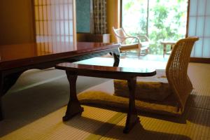 a wooden table and a chair in a room with a window at Yamatoya Besso in Matsuyama
