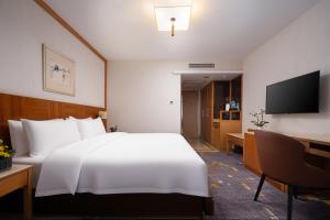 a hotel room with a large white bed and a desk at Liuhua Hotel in Guangzhou +43 photos