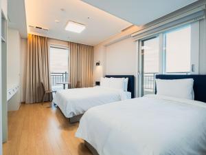 a hotel room with two beds and a balcony at 블루앤호텔 in Songjŏng