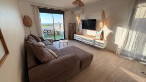 a living room with a couch and a flat screen tv at Au Soleil Couchant in Wimille