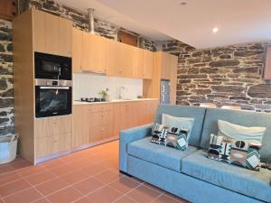 a living room with a blue couch and a kitchen at Quinta da Valdigueira in Armamar