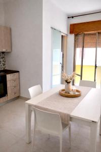a white dining room table with white chairs in a kitchen at My Home Lampedusa in Lampedusa
