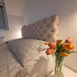 a vase with flowers on a table next to a bed at Garden lux in Belgrade